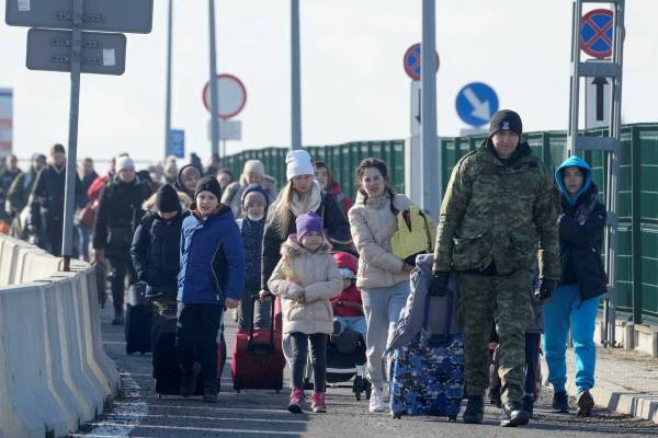 A Polish border guard assists refugees from Ukraine as they arrive to Poland at the Korczowa bo ...