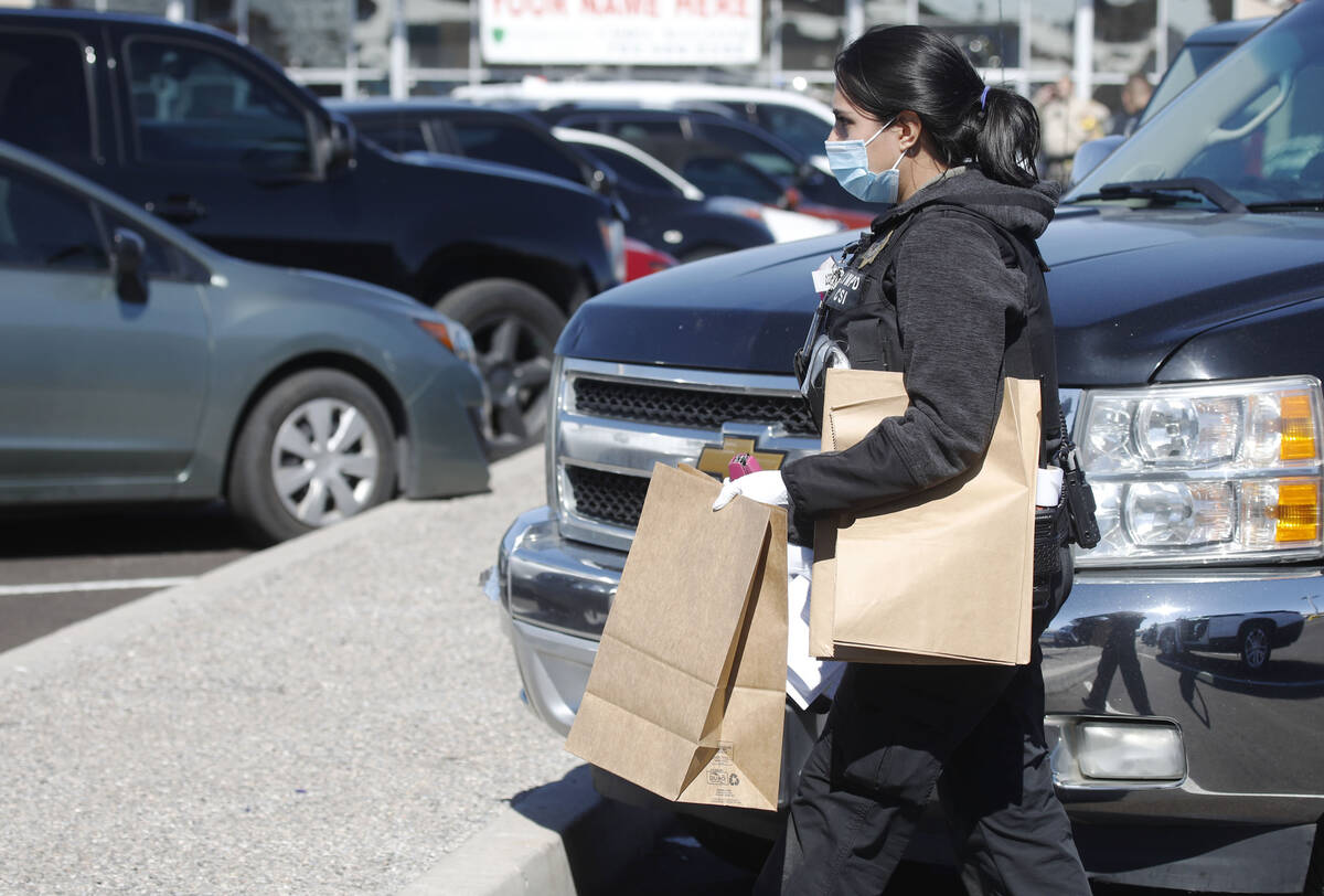 A police office carries brown bags during investigating at Manny's Glow Ultra Lounge & Restaur ...