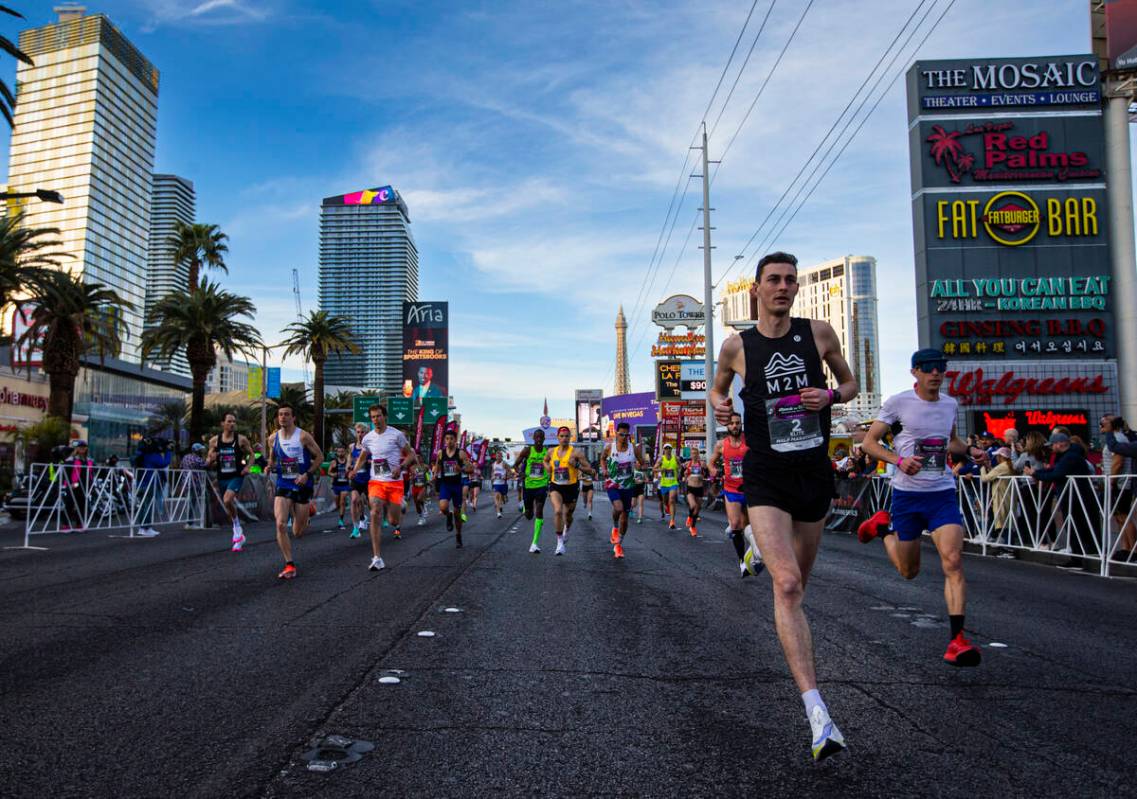 Justin Kent, of Canada, right, leads the group of elite runners on his way to win the Rock &#x2 ...