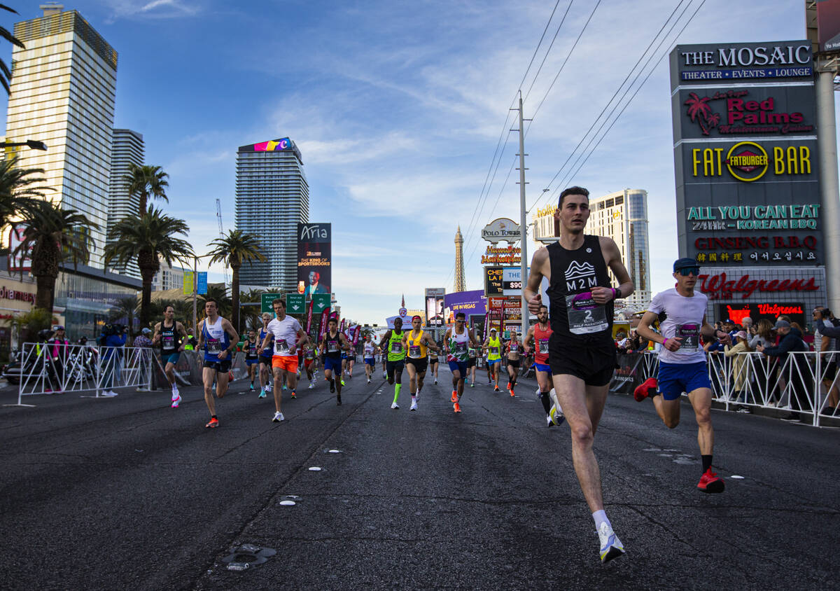 Justin Kent, of Canada, right, leads the group of elite runners on his way to win the Rock &#x2 ...