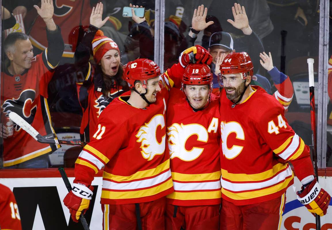 Calgary Flames' Matthew Tkachuk, center, is congratulated by Mikael Backlund, left, and Erik Gu ...