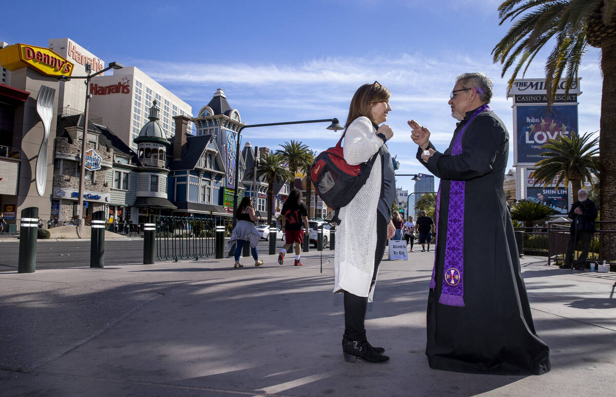 (From right) Priest Jorge Hernandez prays after placing ashes on the forehead of Julie Kelley f ...