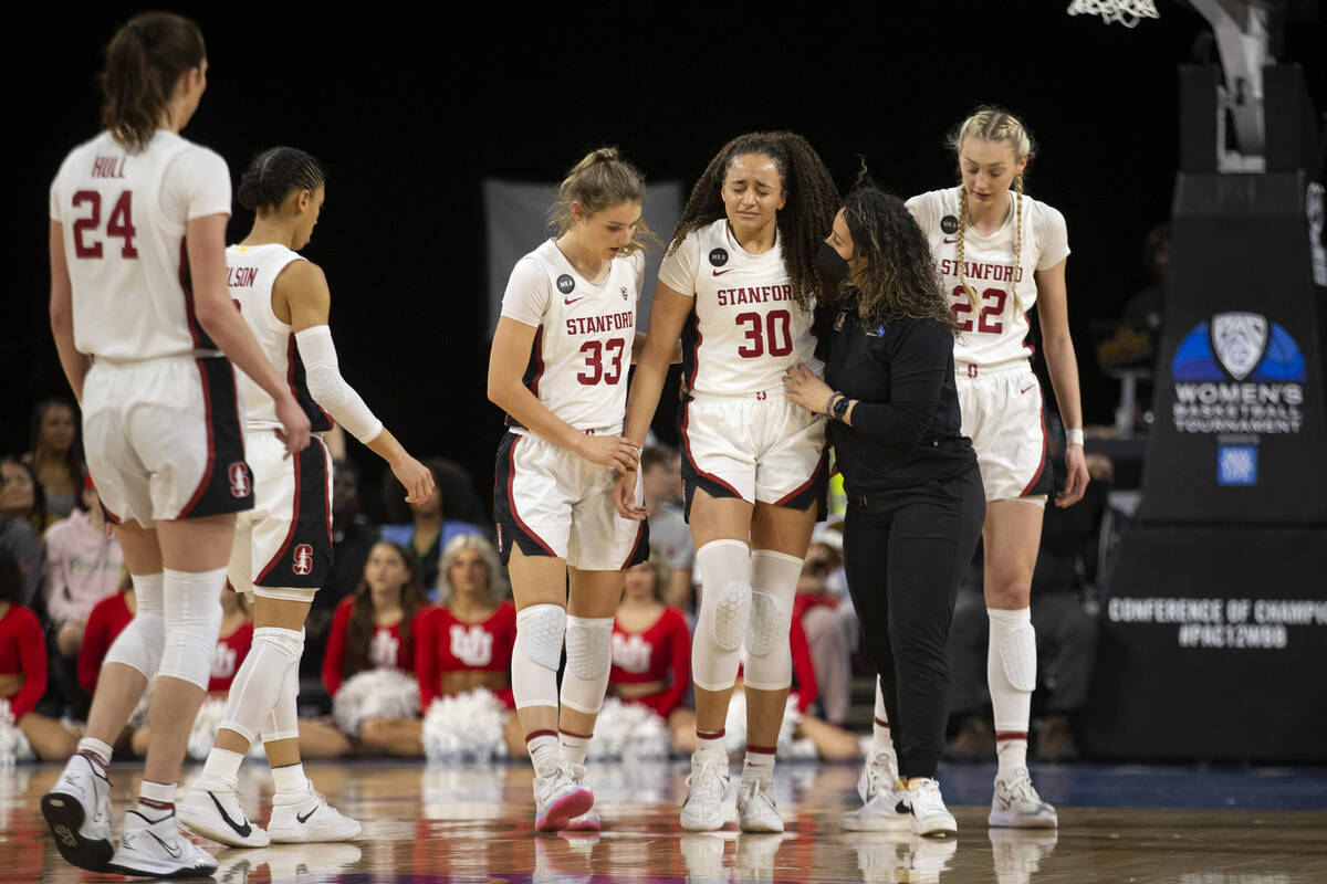 Stanford guard Haley Jones (30) walks off the court with an injury, flanked by guard Hannah Jum ...