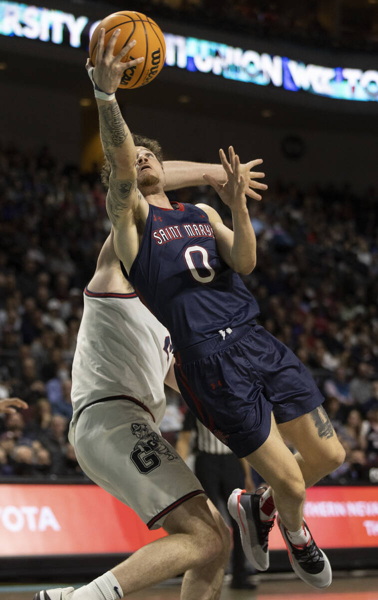 St. Mary's Gaels guard Logan Johnson (0) slices to the rim past Gonzaga Bulldogs center Chet Ho ...