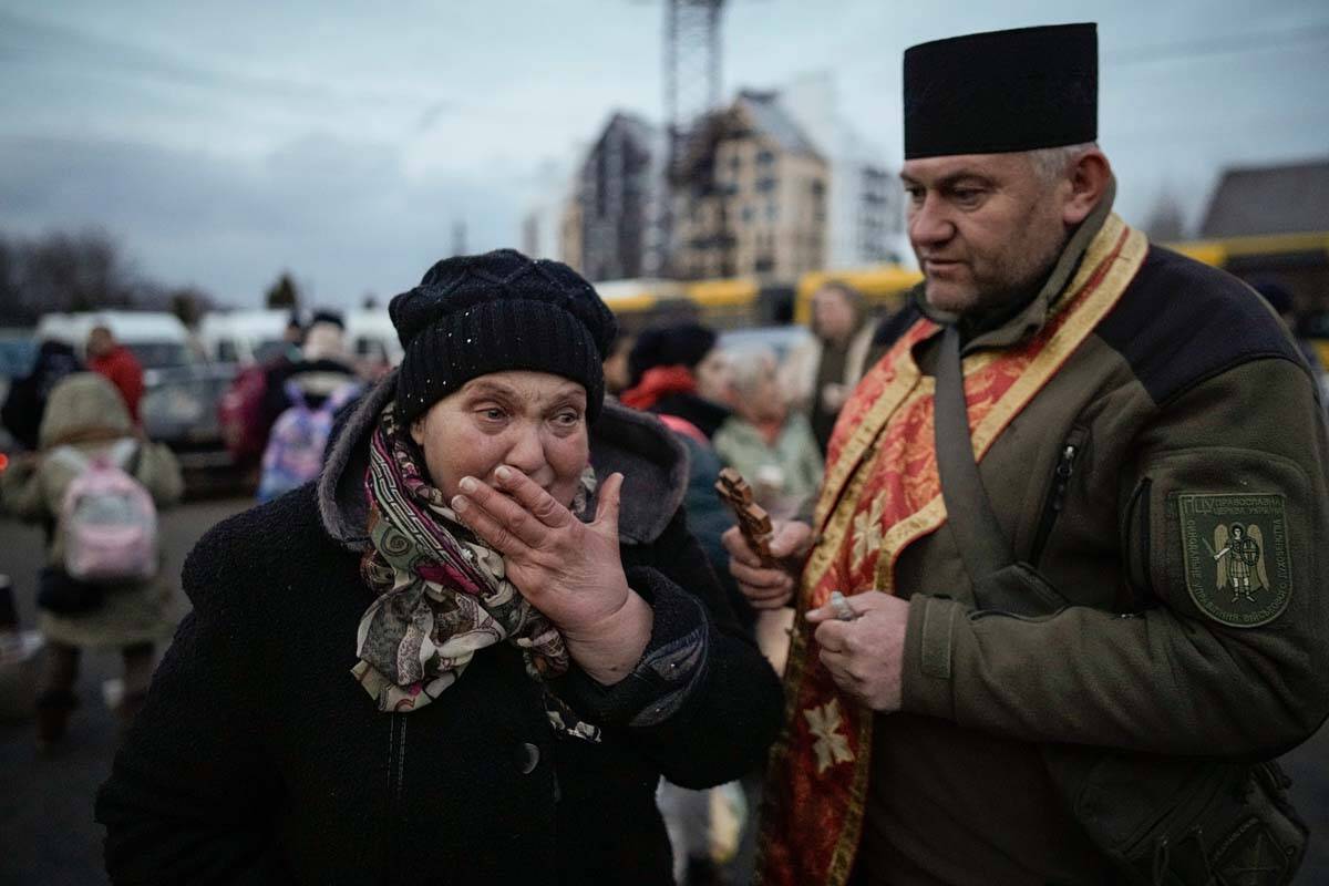 A military priest tries to comfort a crying woman who was evacuated from Irpin, at a triage poi ...