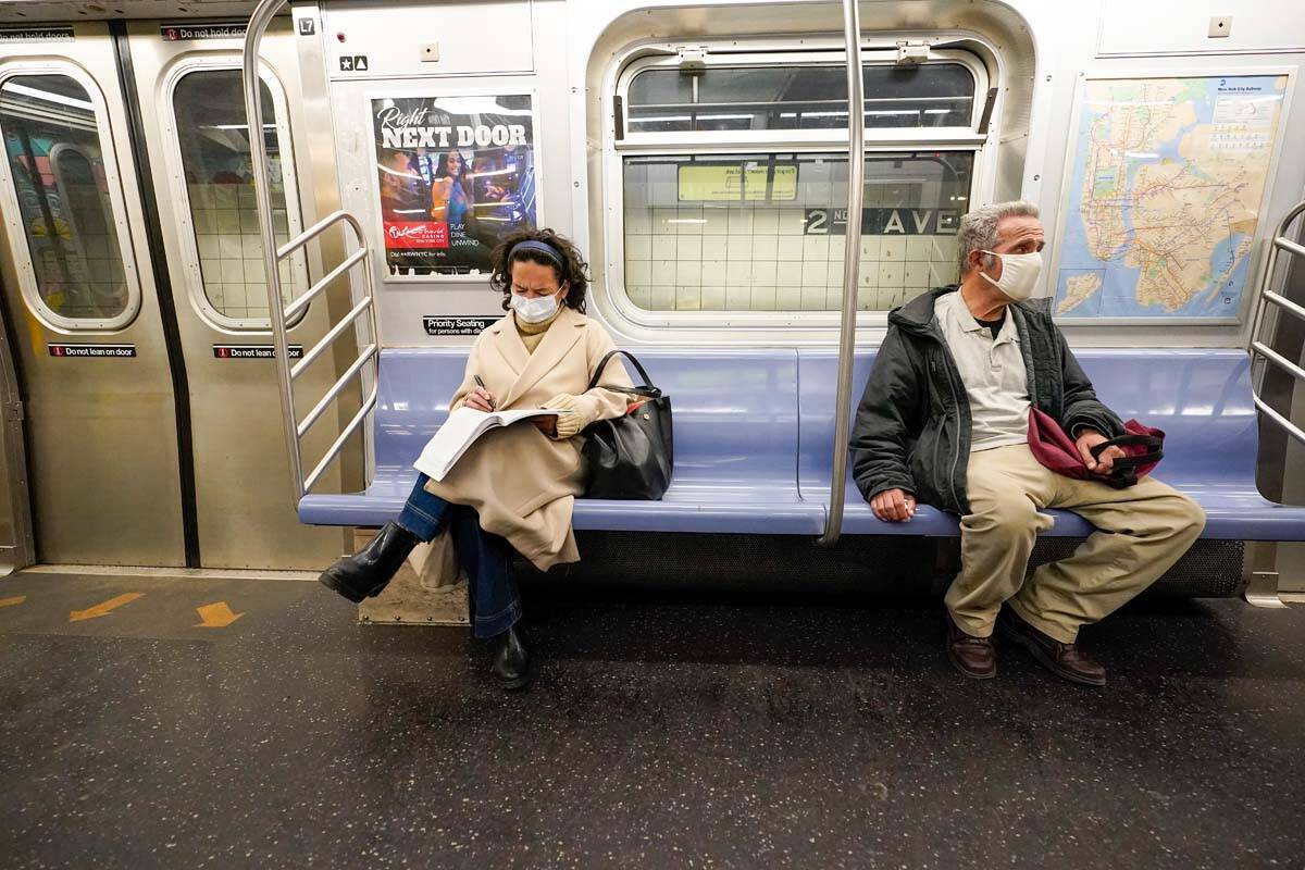 Commuters wear face masks and social distance while riding an M Train, Tuesday, March 9, 2021, ...