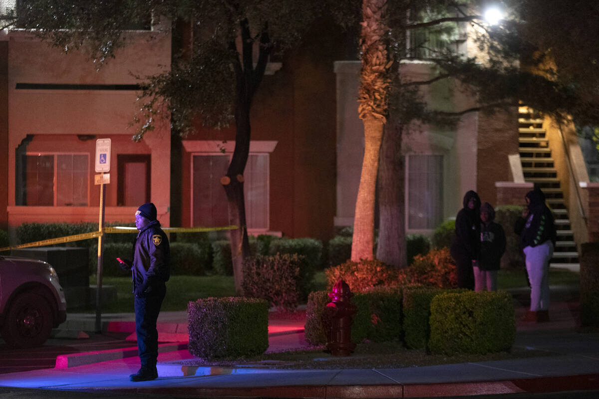 A security guard and bystanders watch as Metropolitan police investigate a homicide at a gated ...