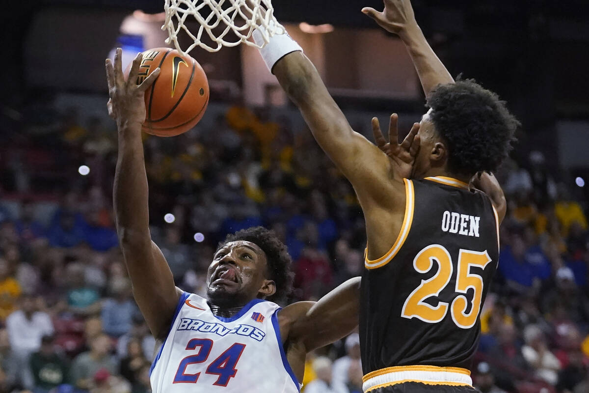 Boise State forward Abu Kigab (24) goes to the basket as Wyoming forward Jeremiah Oden (25) def ...