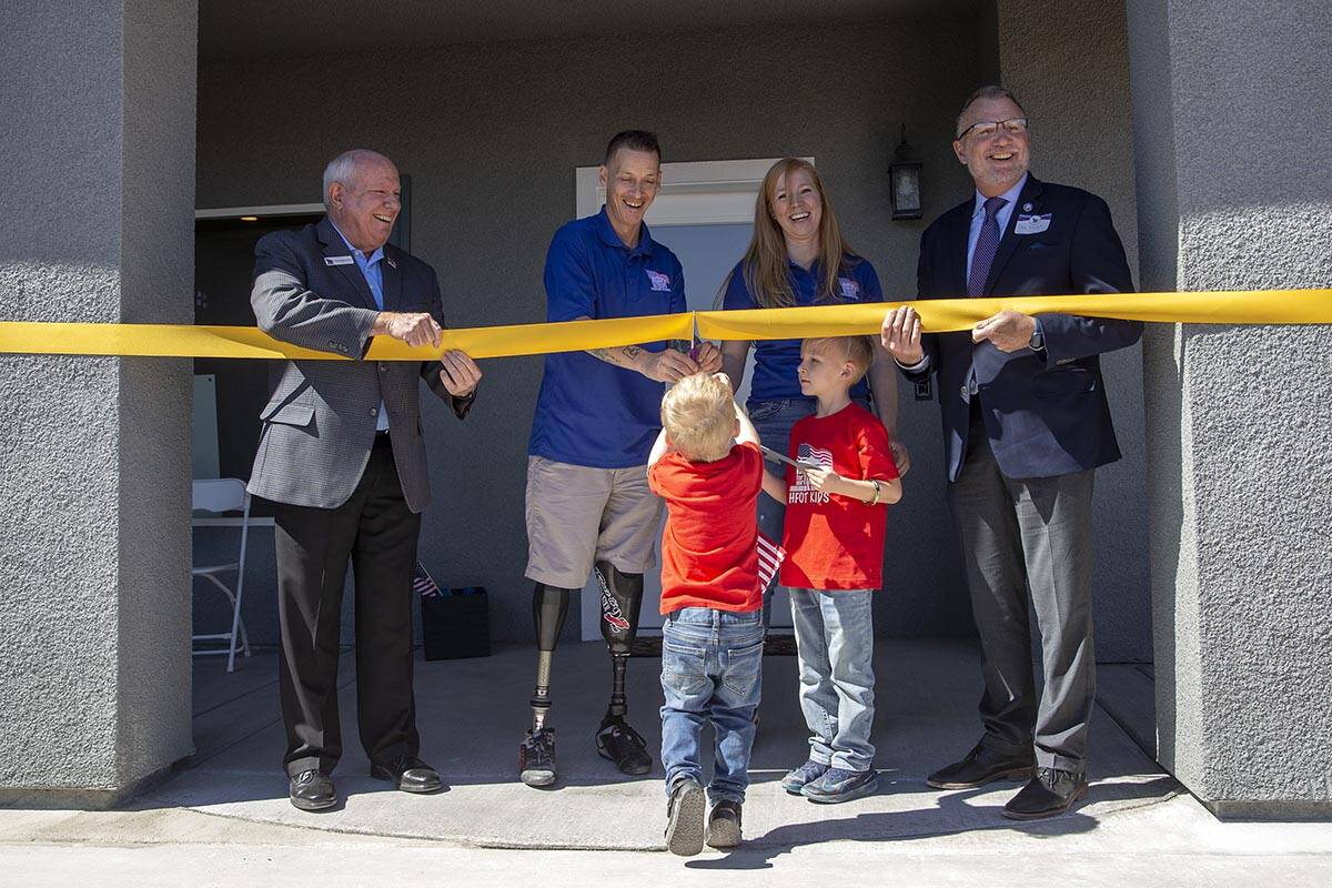 Army Sergeant Adam Poppenhouse and his family cut the ribbon in front of their new home donated ...