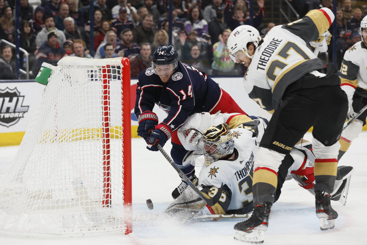 Vegas Golden Knights' Logan Thompson, bottom left, makes a save against Columbus Blue Jackets' ...