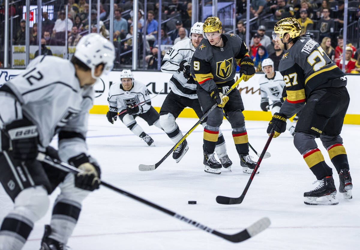 Golden Knights center Jack Eichel (9) pushes the puck to teammate defenseman Shea Theodore (27) ...