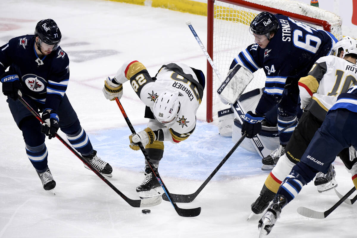 Vegas Golden Knights' William Carrier (28) tries to control the puck as Winnipeg Jets' Evgeny S ...