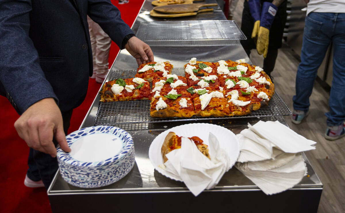 Attendees grab slices of pizza at the Marra Forni Brick Oven Cooking Solutions booth during the ...