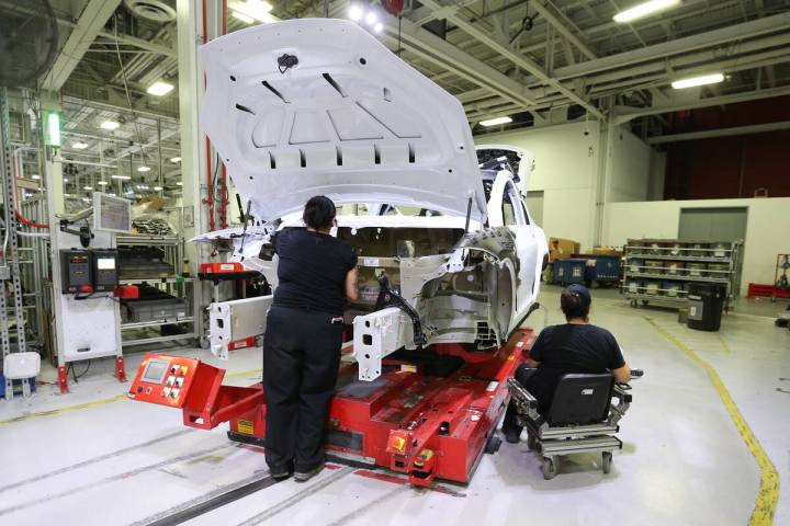 Production associates work on a Tesla Model 3 at the Tesla factory in Fremont, California, on J ...