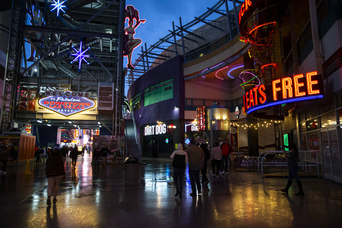 People pass by Neonopolis at Fremont Street as rain falls on Monday, March 28, 2022, in downtow ...