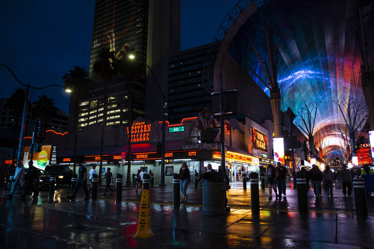 People walk along Fremont Street as rain falls on Monday, March 28, 2022, in downtown Las Vegas ...