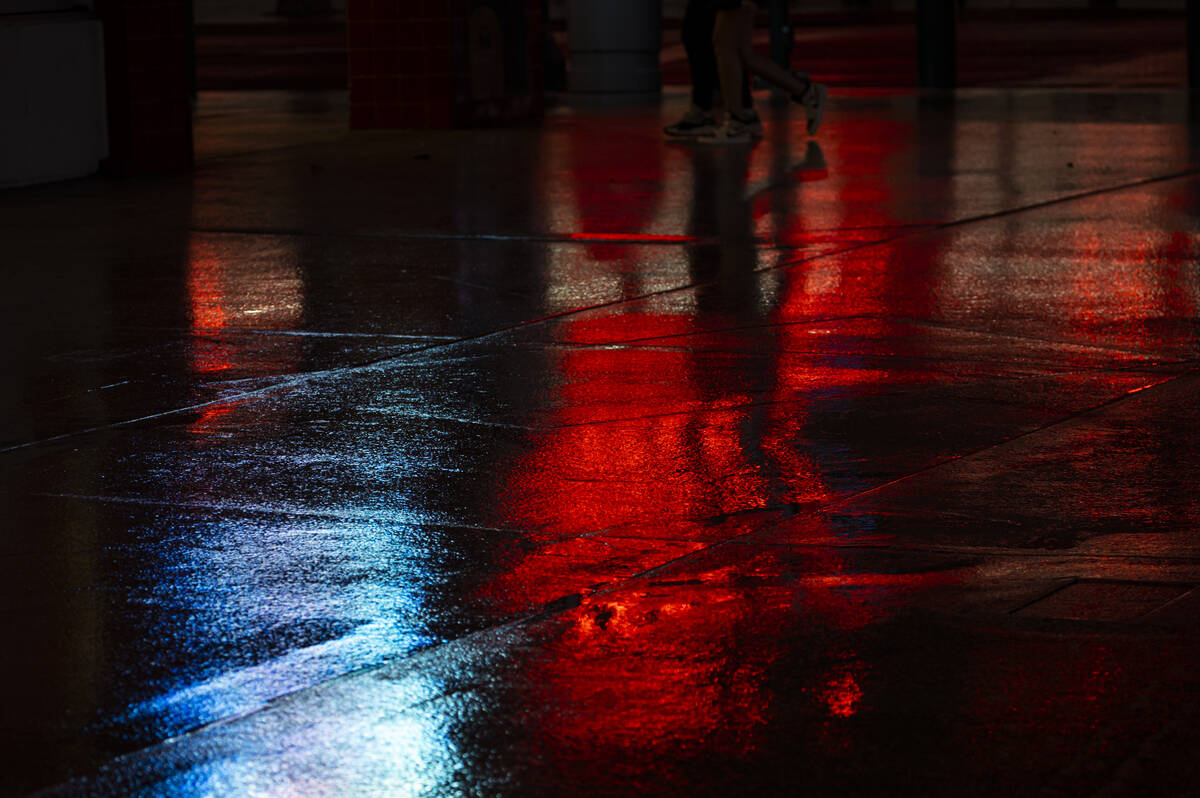 Neon and screen displays reflect in water as rain falls along Fremont Street on Monday, March 2 ...