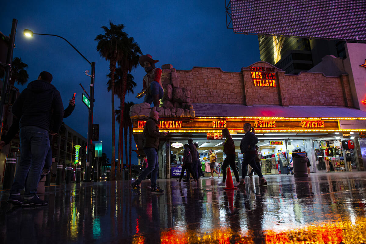 People walk along Fremont Street as rain falls on Monday, March 28, 2022, in downtown Las Vegas ...