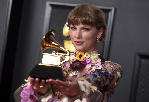 Taylor Swift poses in the press room with the award for album of the year for "Folklore&qu ...