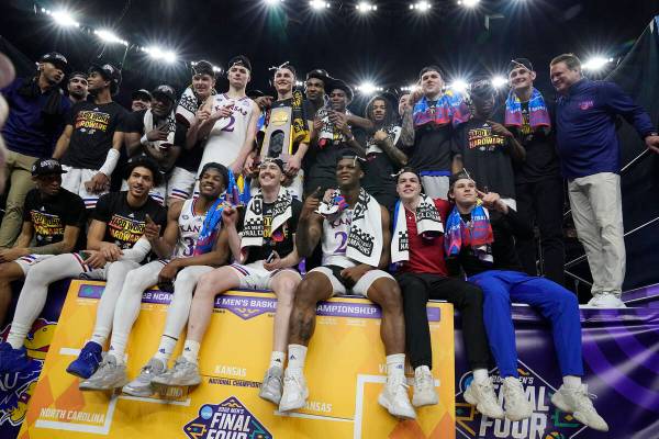 Kansas players pose with the trophy after defeating North Carolina in a college basketball game ...