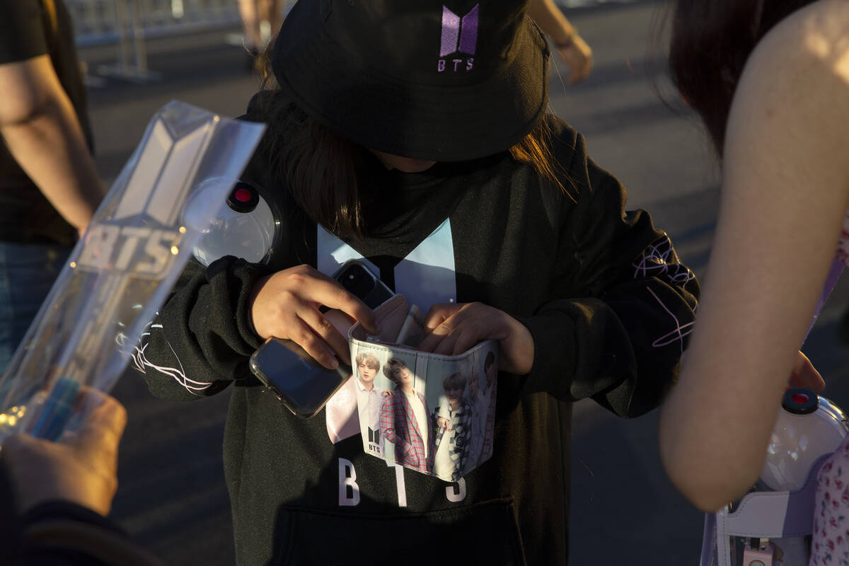 A young BTS fans reaches into her band-themed wallet to purchase merchandise outside of Allegia ...