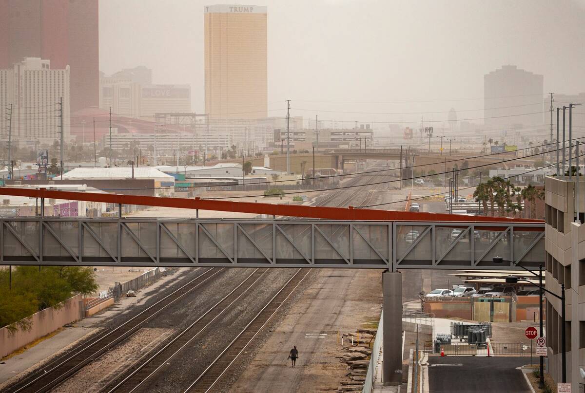 A man walks alongside train tracks as winds bring in a dust storm on Monday, April 11, 2022, ov ...