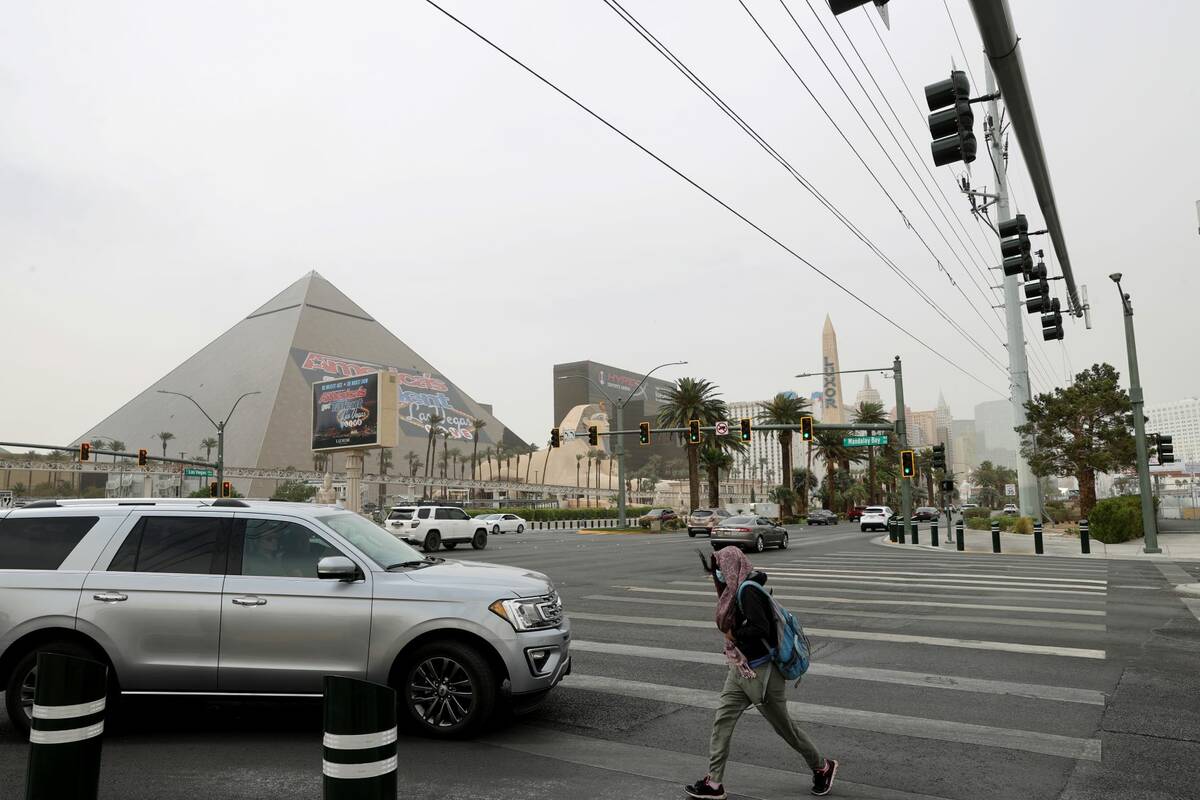 A pedestrian braves high winds and dust on the Strip at Mandalay Bay Drive in Las Vegas Monday, ...