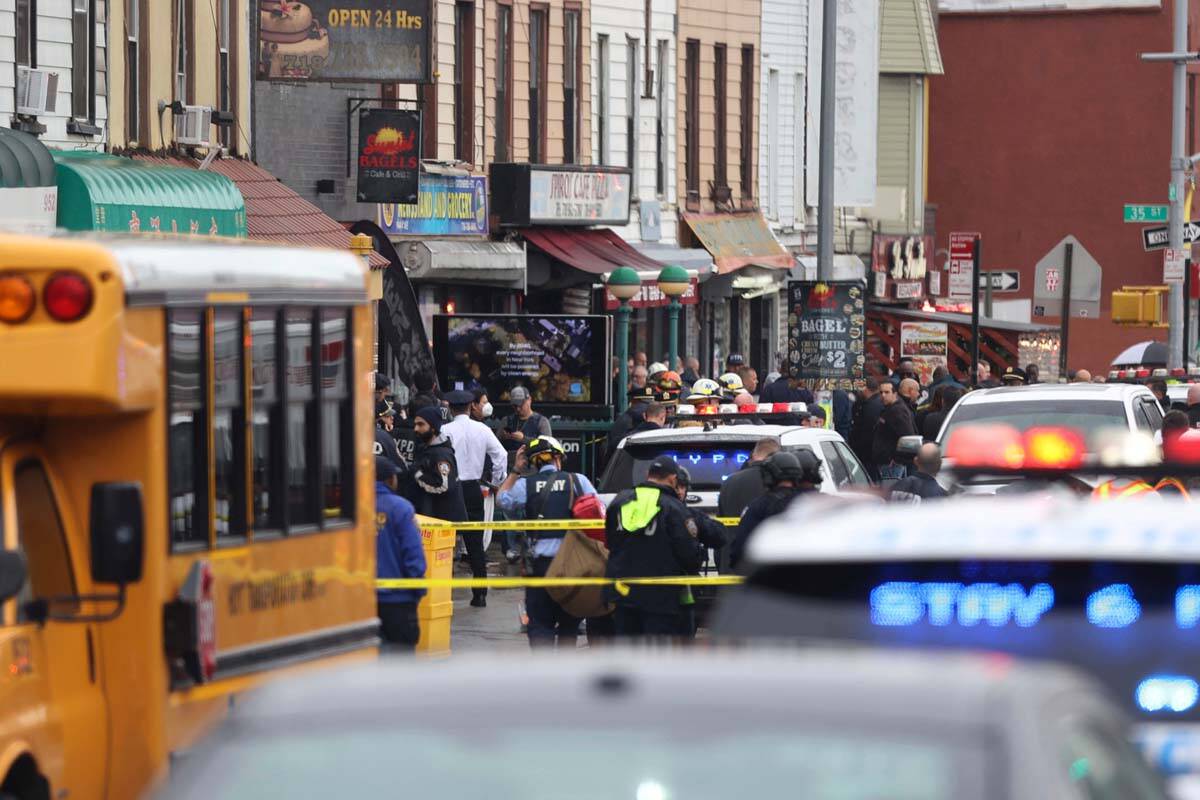 Law enforcement gather near the entrance to a subway stop in the Brooklyn borough of New York, ...