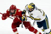 Michigan's Brendan Brisson (19) checks Denver's Jack Devine (4) during the first period of an N ...