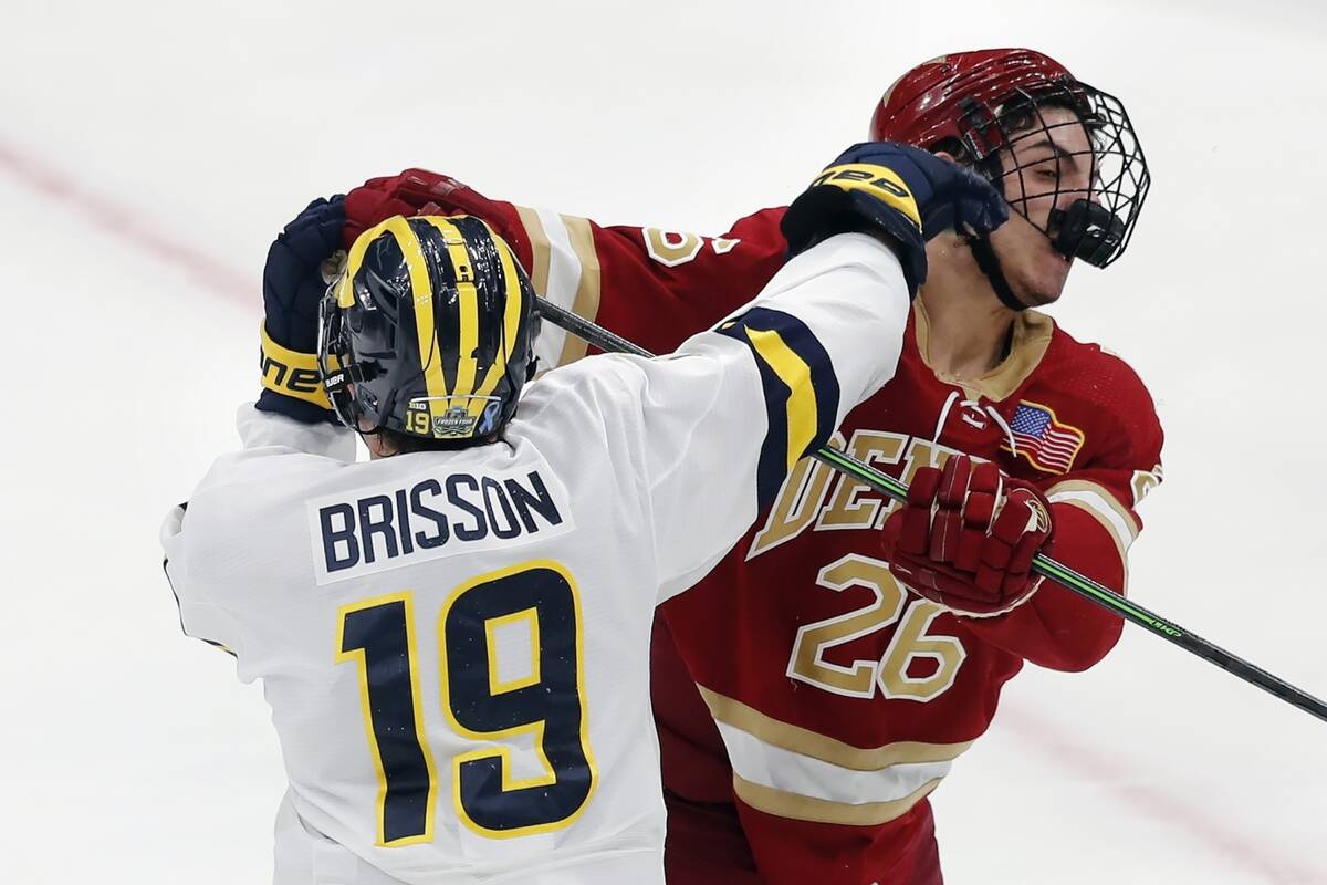 Michigan's Brendan Brisson (19) and Denver's Shai Buium (26) scuffle during the first period of ...