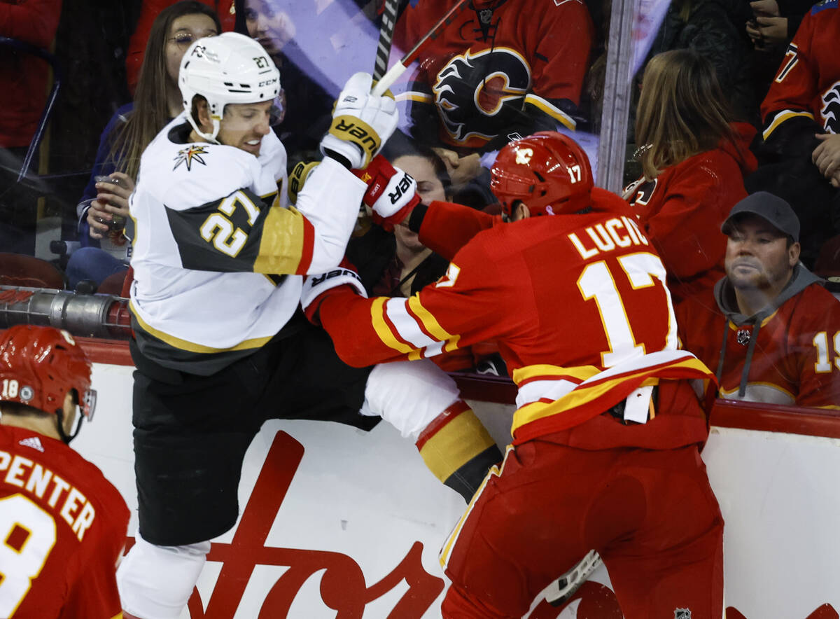 Vegas Golden Knights' Shea Theodore, left, is checked by Calgary Flames' Milan Lucic during sec ...