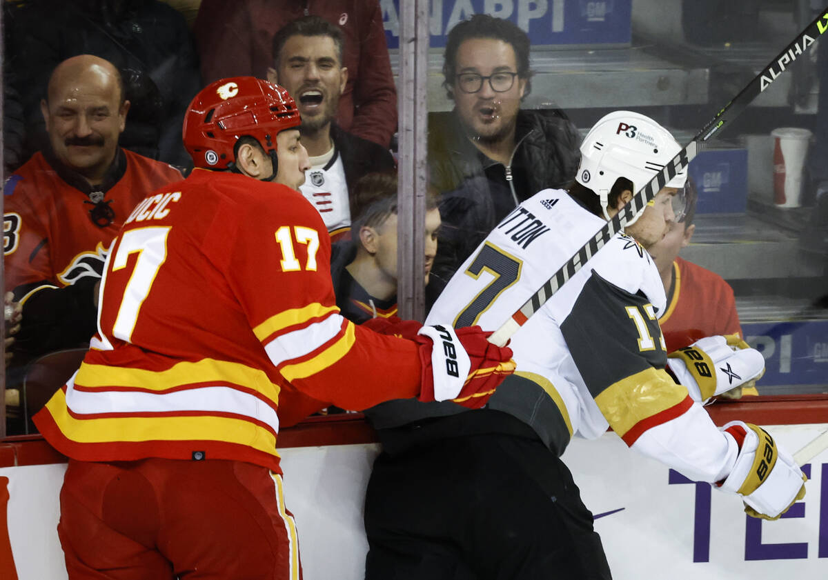 Vegas Golden Knights' Ben Hutton, right, is checked by Calgary Flames' Milan Lucic during first ...