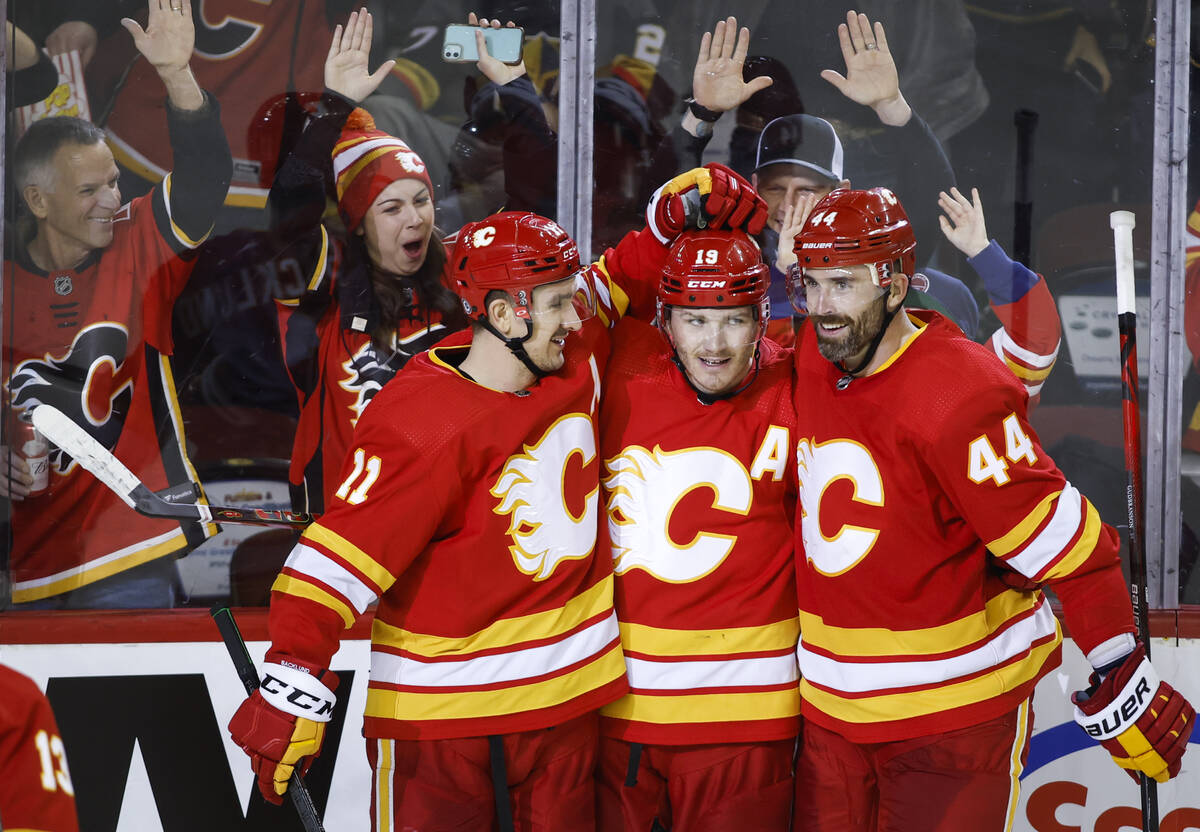 Calgary Flames' Matthew Tkachuk, center, is congratulated by Mikael Backlund, left, and Erik Gu ...