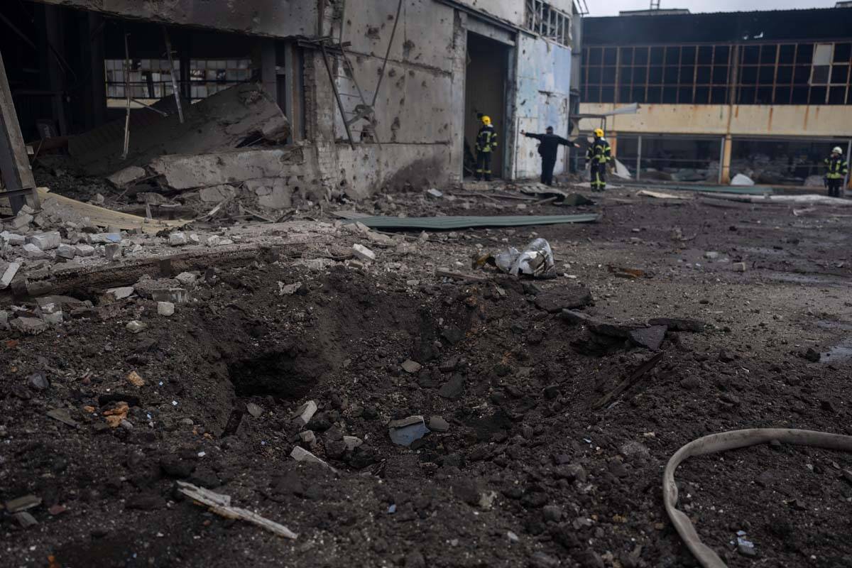 A crater is seen following Russian bombing as firefighters try to extinguish the fire at a dama ...