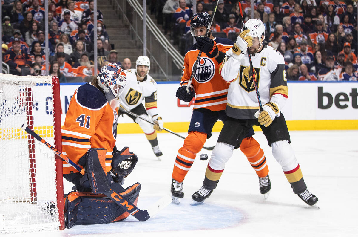 Vegas Golden Knights' Mark Stone (61) and Edmonton Oilers' Darnell Nurse (25) battle in front a ...