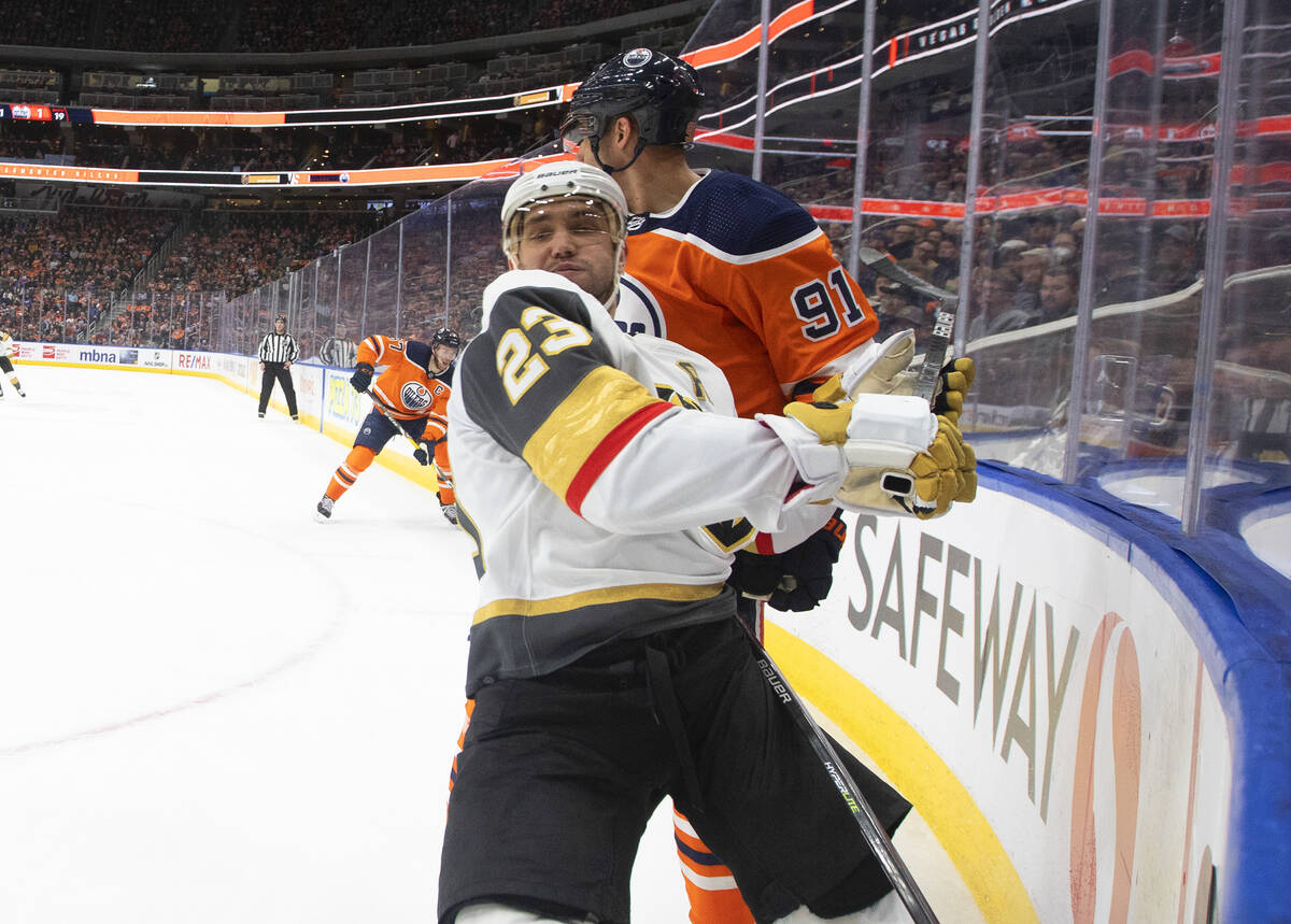 Vegas Golden Knights' Alec Martinez (23) is checked by Edmonton Oilers' Evander Kane (91) durin ...