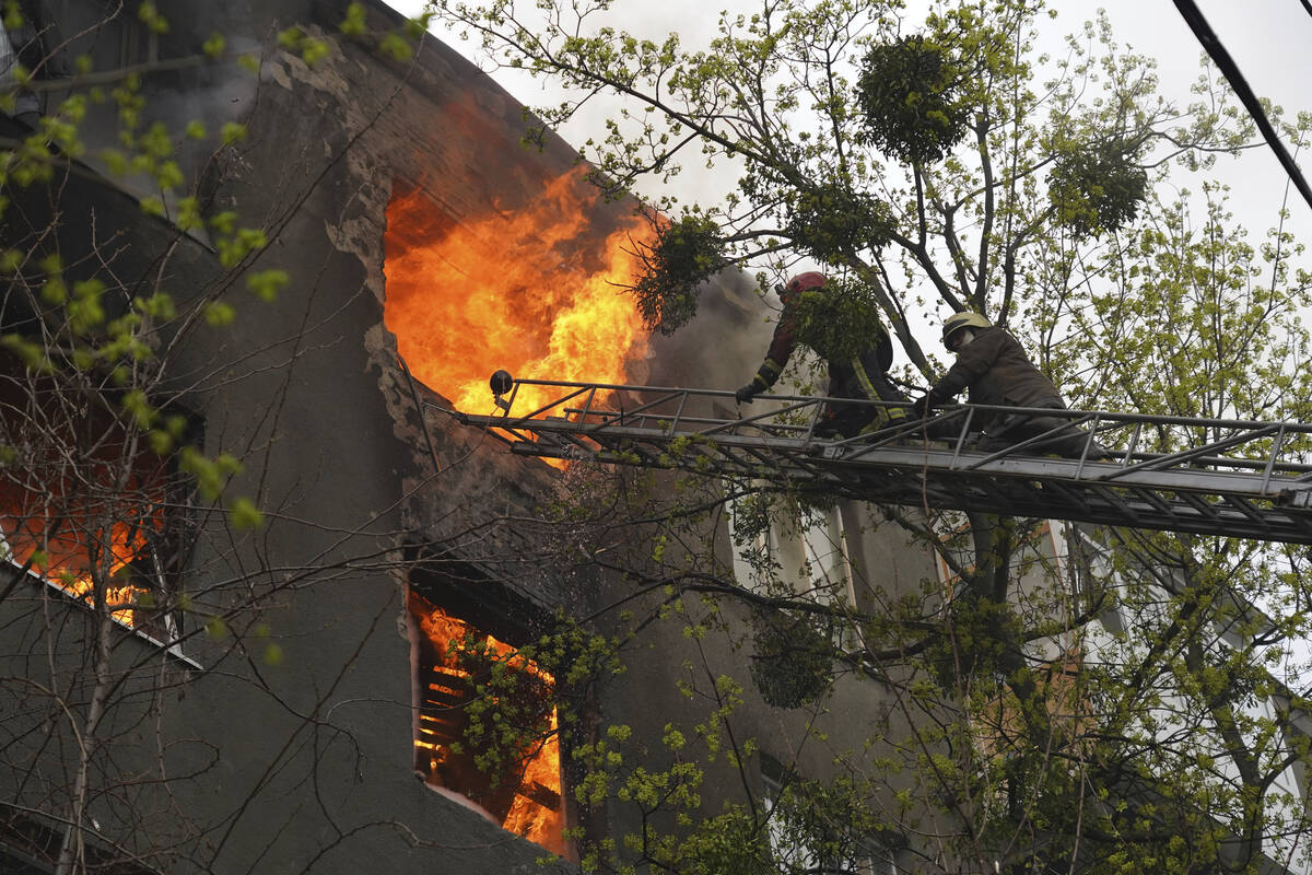 Firefighters work to extinguish fire at an apartments building after a Russian attack in Kharki ...