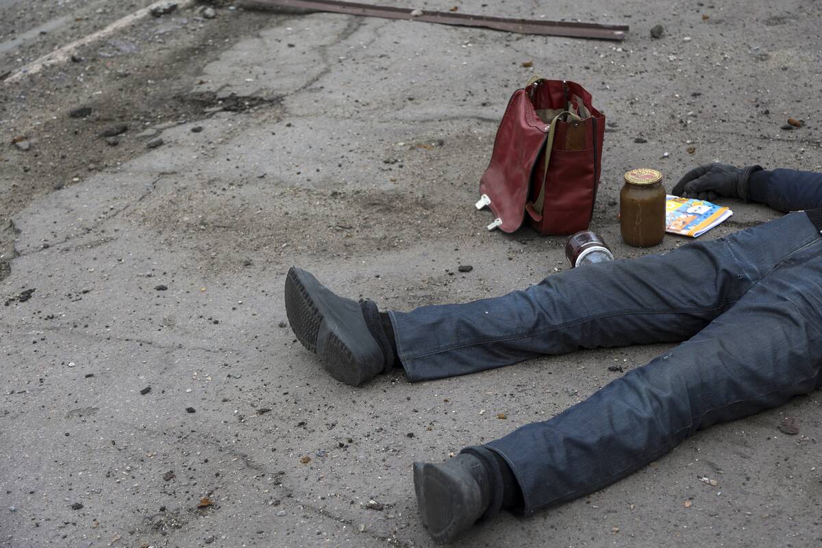 The body of a civilian lies on the ground at a bus stop not far from a destroyed during a heavy ...