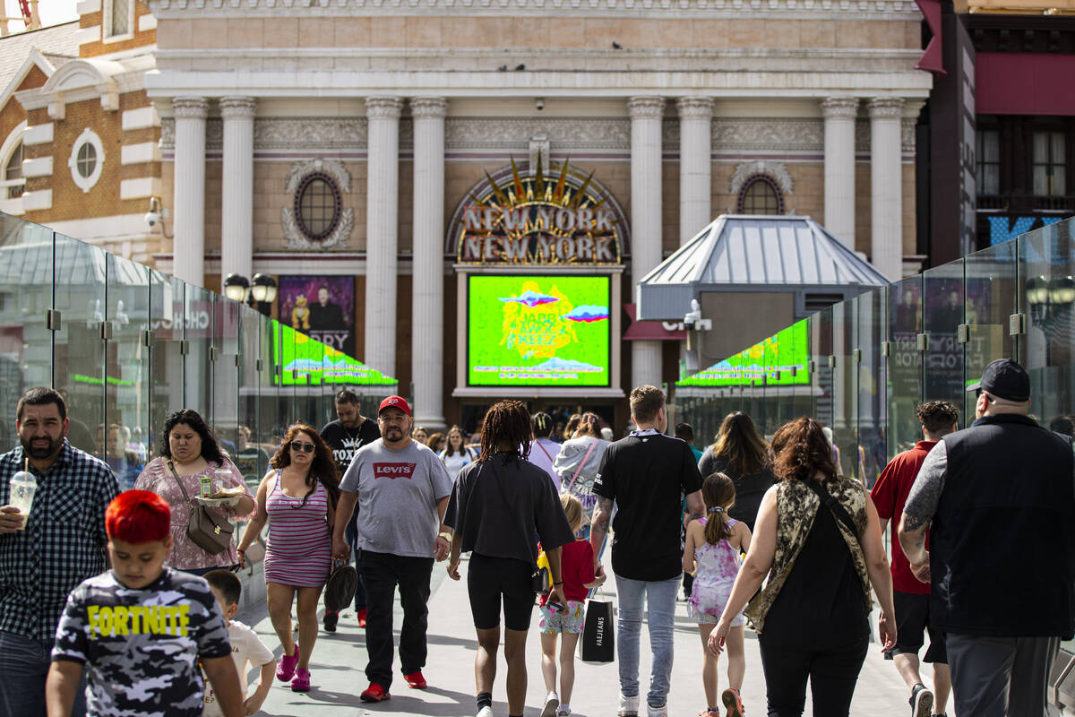 People walk along the pedestrian bridge between the New York-New York and the MGM Grand on Mond ...