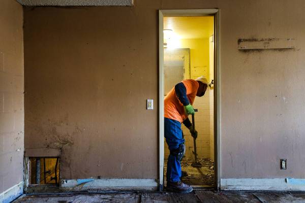 Juan Amador removes tiles in a bathroom of an apartment at the former Share Village 1 property ...