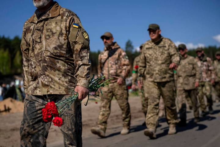 Irpin Territorial Defence and Ukrainian Army soldiers hold flowers to be placed on the graves o ...