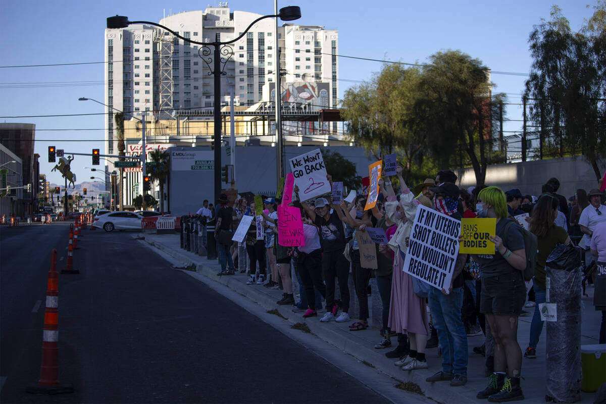 Attendees of a rally in support of abortion rights show their signs to passing motorists outsid ...