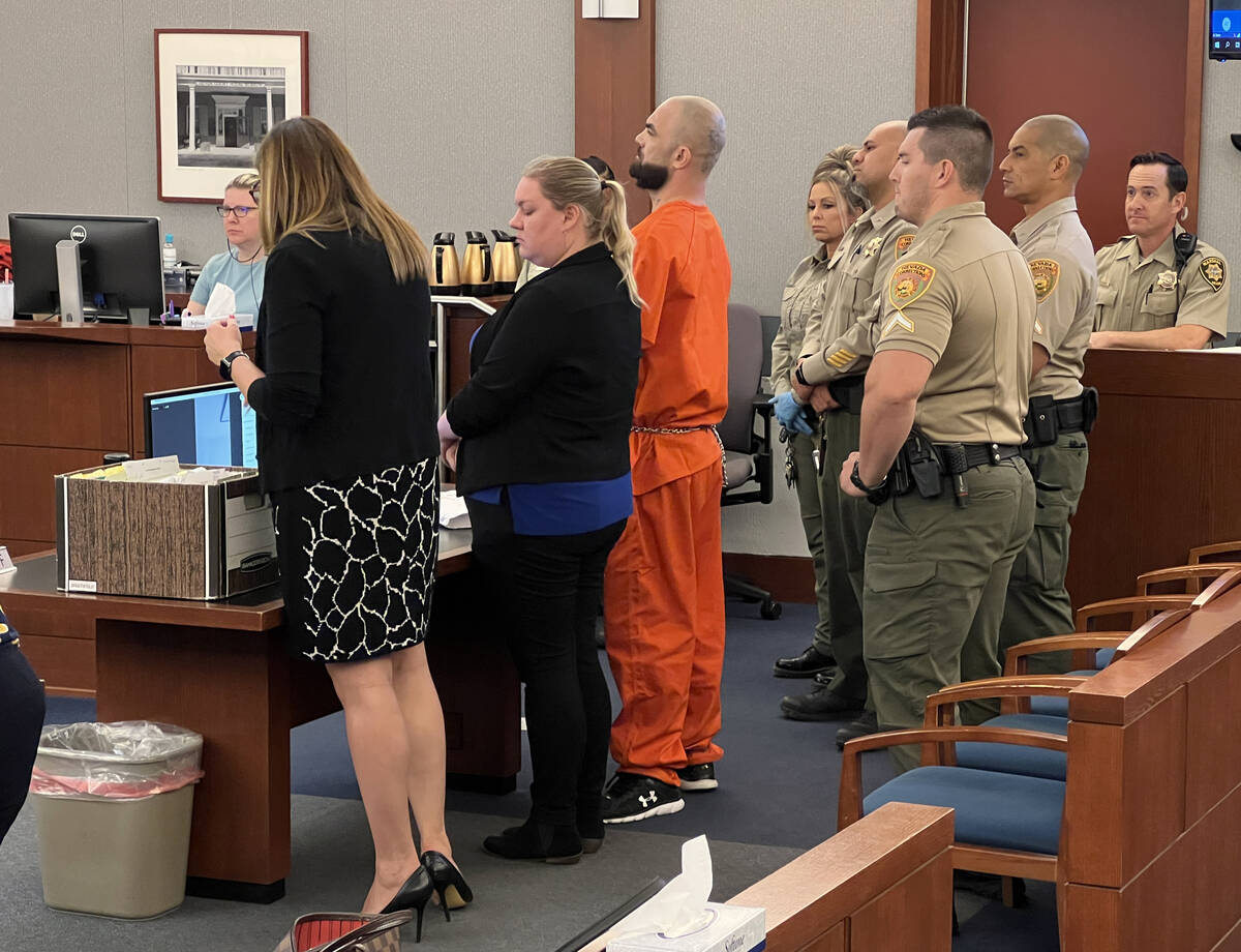 Shawn Eisenman, center in orange jumpsuit, is watched by multiple officers during an appearance ...