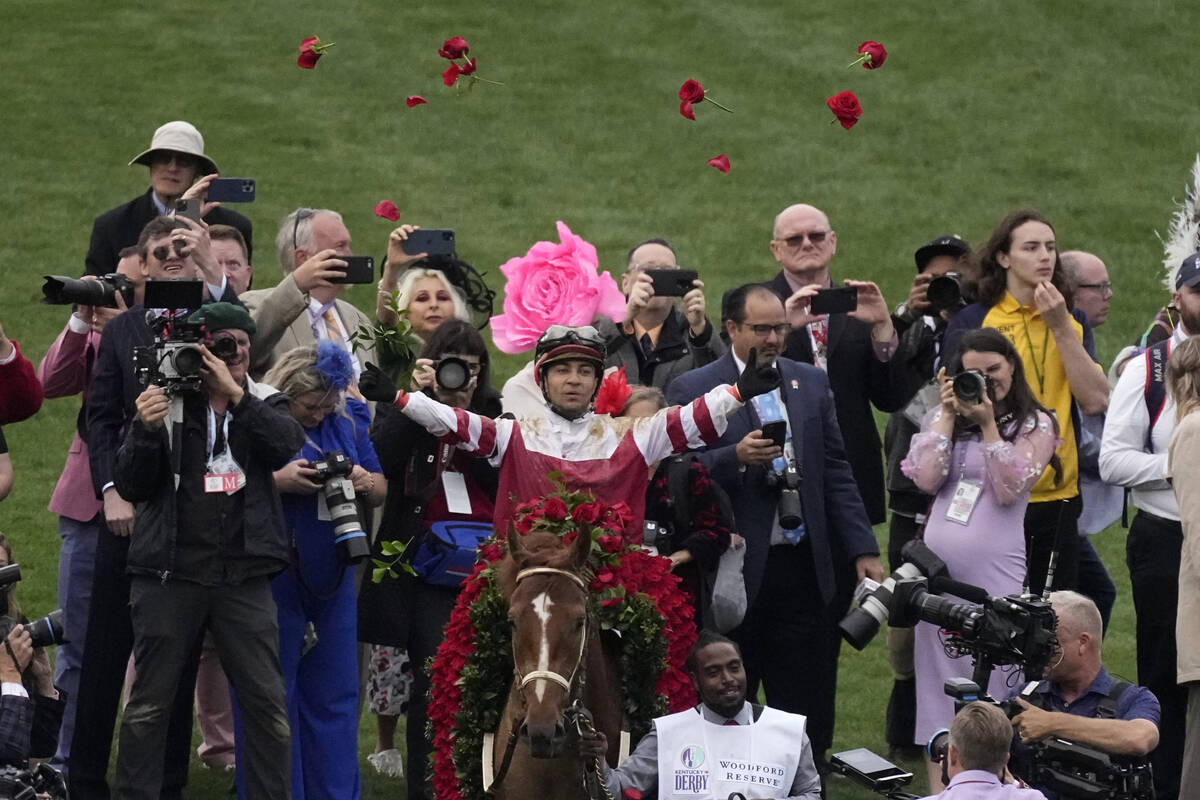 Jockey Sonny Leon tosses roses into the air as he rides Rich Strike to the winner's circle afte ...