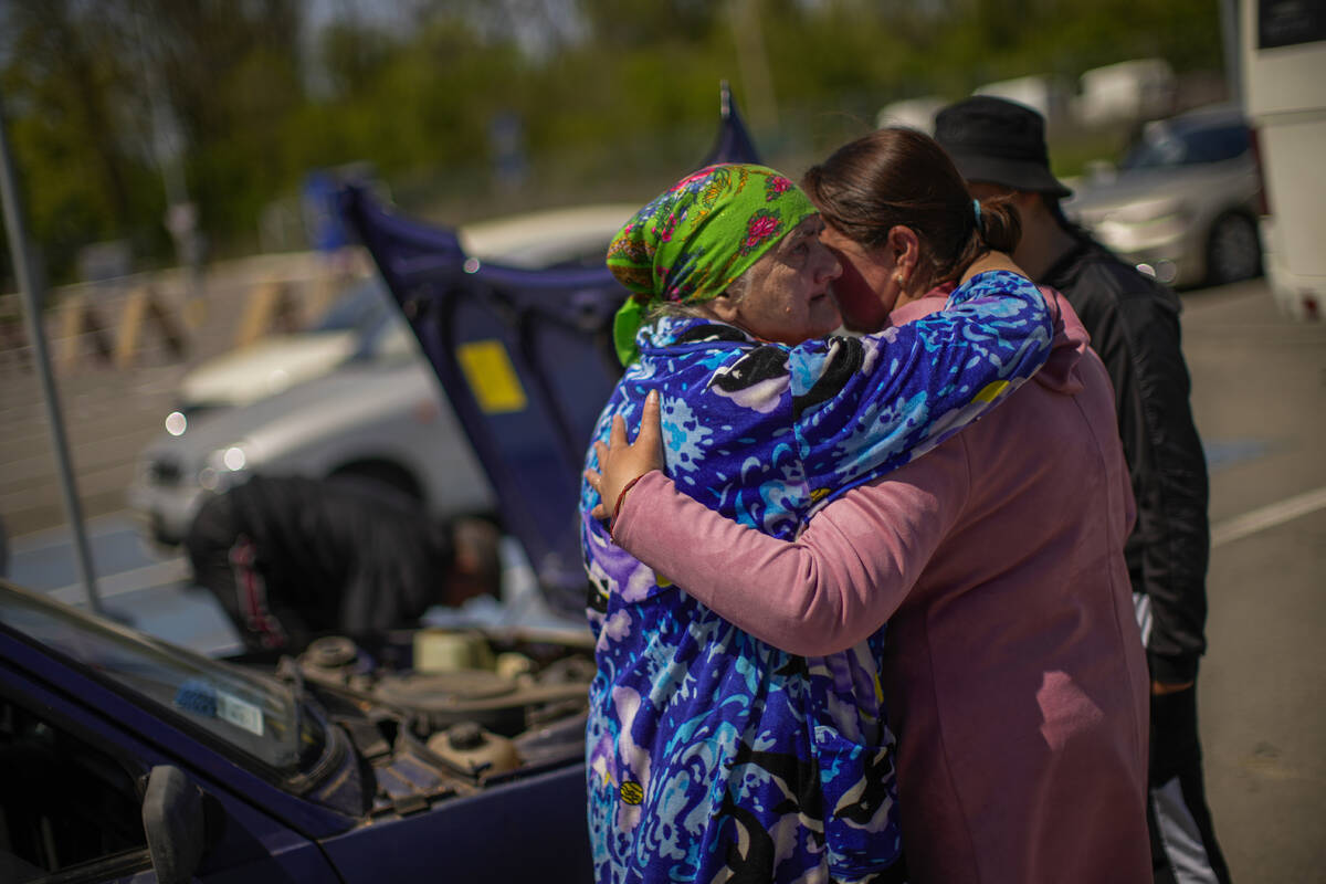 A family who fled from Myrne in a towed car work on repairing it upon their arrival to a recept ...