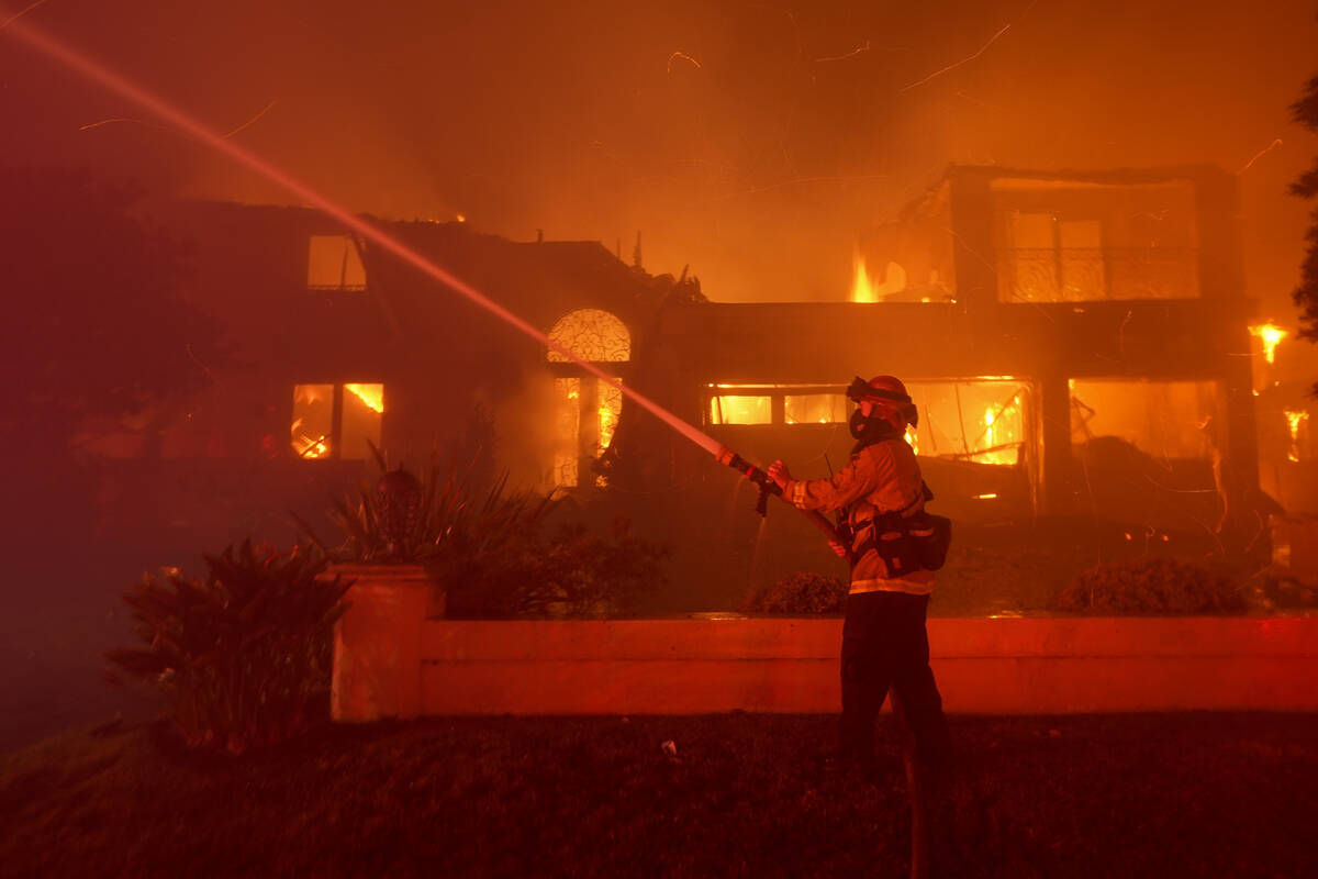 A firefighter works to put out a structure burning during a wildfire Wednesday, May 11, 2022, i ...