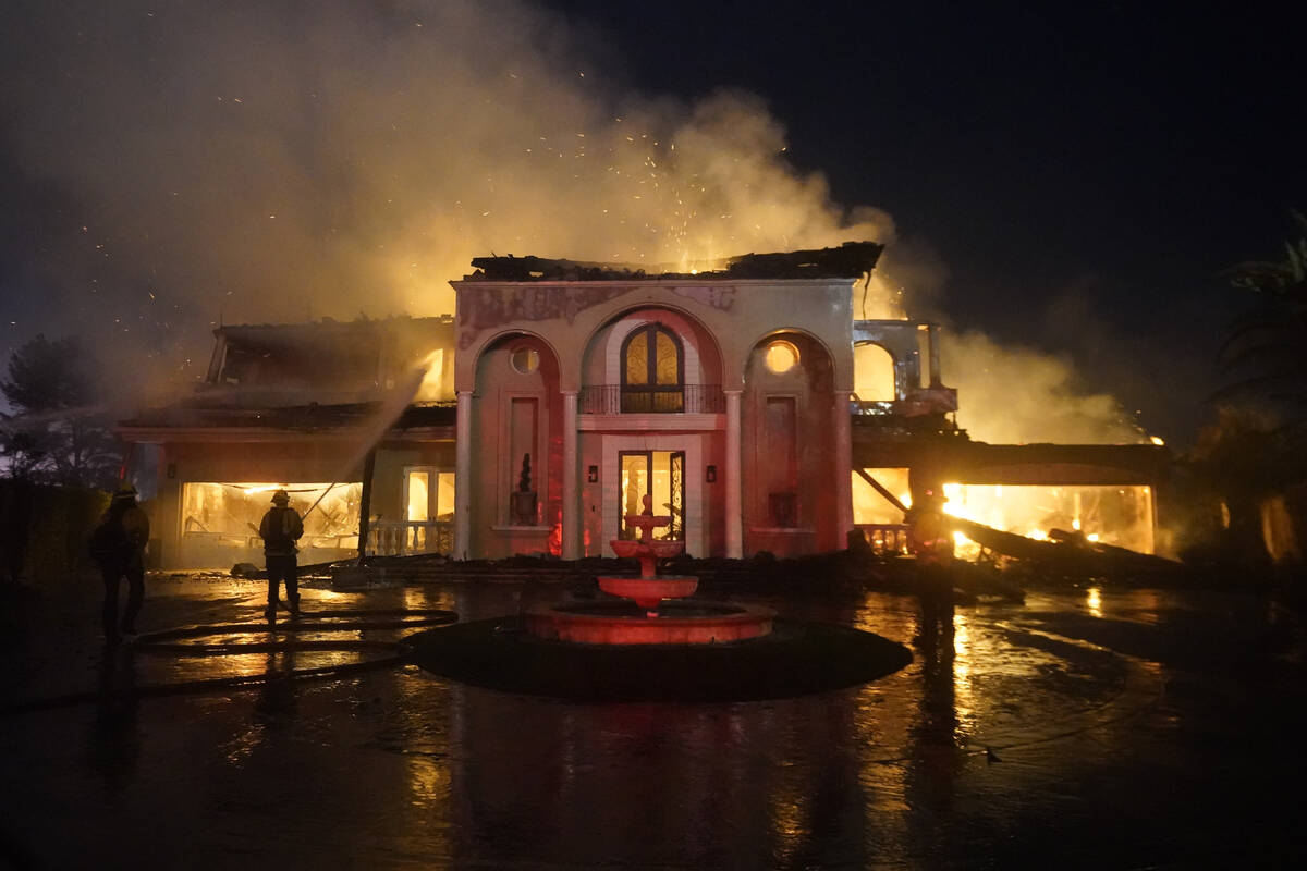 Firefighters work to put out a structure burning during a wildfire Wednesday, May 11, 2022, in ...