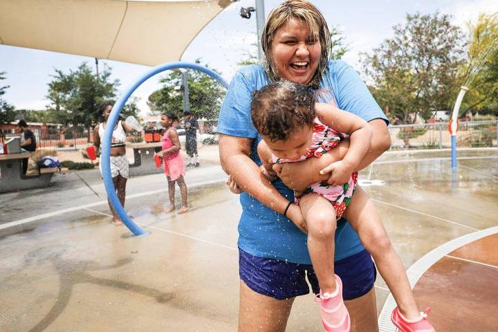 Stephanie Ramirez holds her daughter Raylee Brown, 2, as they play in the water at Baker Park i ...