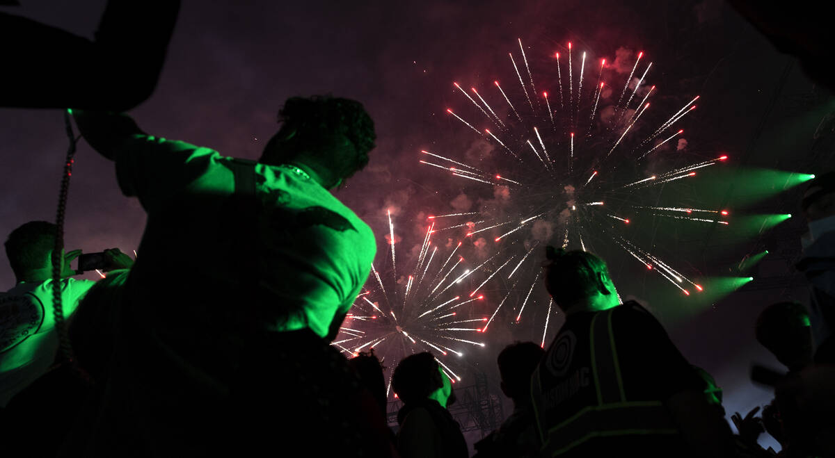 Attendees photograph the fireworks show during the second day of the Electric Daisy Carnival at ...