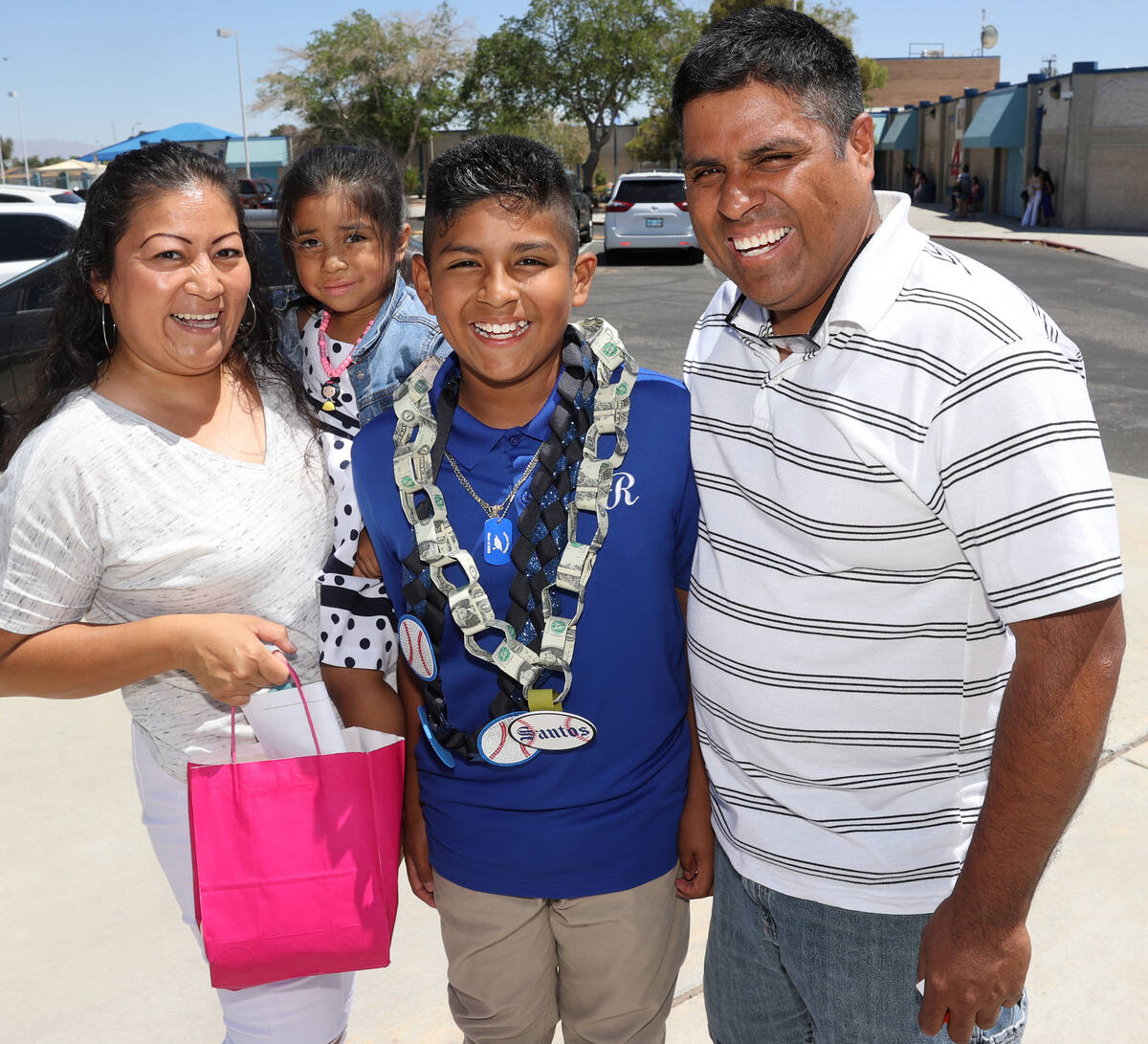 Fifth grade graduate Santos Marin, 10, shows off his money lei with his family, mom Lourdes, si ...